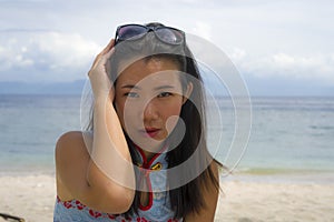 Young beautiful and happy Asian Korean woman in chic Summer dress and sunglasses posing relaxed as tourist at tropical beach