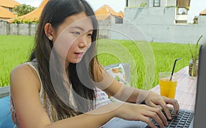 Young beautiful and happy Asian Korean woman working outdoors with laptop computer networking green grass background cafe as digit