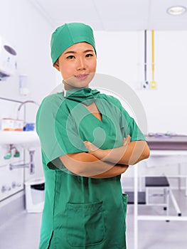 Young beautiful and happy Asian medicine doctor or chief hospital nurse in green scrubs and surgeon hat smiling confident at