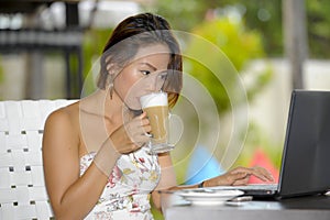 Beautiful happy woman in Summer dress outdoors at nice coffee shop having breakfast networking or working with laptop computer