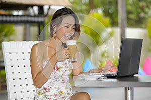 Beautiful happy woman in Summer dress outdoors at nice coffee shop having breakfast networking or working with laptop computer