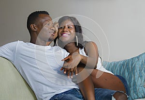 Young beautiful and happy black afro American couple in love relaxed at home living room sofa couch smiling cheerful having fun