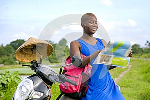 Young beautiful and happy black afro american tourist woman with scooter motorbike looking to road map searching destination explo