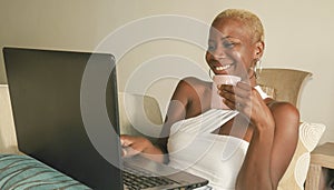 Young beautiful and happy black afro American woman smiling excited having fun on internet using social media on laptop computer