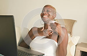 Young beautiful and happy black afro American woman smiling excited having fun on internet using social media on laptop computer