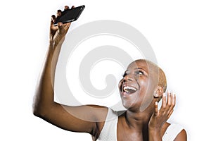 Young beautiful and happy black afro American woman smiling excited taking selfie picture portrait with mobile phone or recording