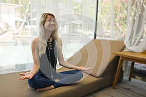 Young beautiful and happy blond woman at resort  pool bed sitting on lotus position practicing yoga and meditation in harmony