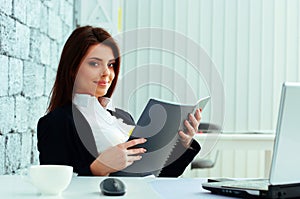 Young beautiful happy businesswoman holding the notebook