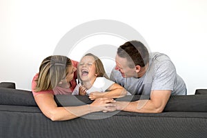 young beautiful and happy Caucasian couple with mother and father playing tickles on cheerful adorable 7 years old blond little g
