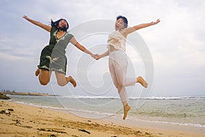 Young beautiful and happy couple of attractive Asian Korean women jumping on the air together at the beach enjoying holidays