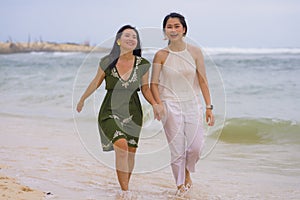 Young beautiful and happy couple of attractive Asian Korean women walking together relaxed at the beach enjoying holidays in gay