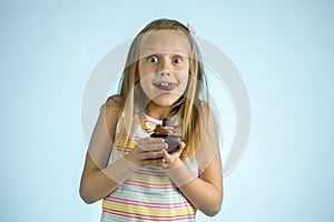 Young beautiful happy and excited blond girl 8 or 9 years old holding chocolate cake on her hand looking spastic and cheerful in s