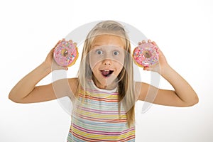 Young beautiful happy and excited blond girl 8 or 9 years old holding two donuts playing cheerful in sugar calories and unhealthy