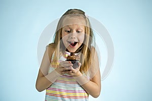 Young beautiful happy and excited blond girl 8 or 9 years old holding chocolate cake on her hand looking spastic and cheerful in s