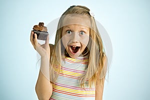 Young beautiful happy and excited blond girl 8 or 9 years old holding chocolate cake on her hand looking spastic and cheerful in s