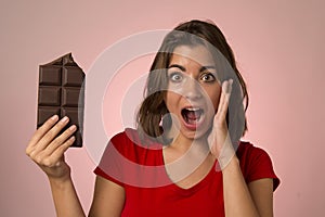 Young beautiful happy and excited woman holding big chocolate ba