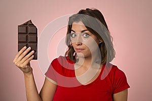 Young beautiful happy and excited woman holding big chocolate ba