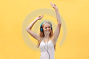 Young beautiful happy girl with hand in the air portrait isolated on yellow background.