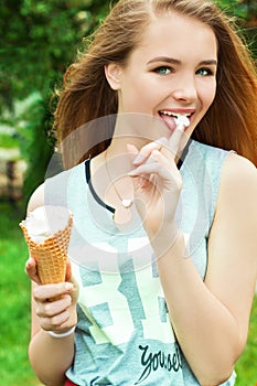 Young beautiful happy girl with long hair in a Sunny day walking around the city and eat ice cream