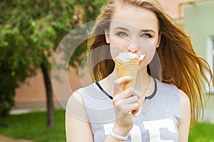 Young beautiful happy girl with long hair in a Sunny day walking around the city and eat ice cream