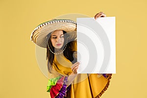 Young beautiful happy girl in sombrero isolated over yellow background.