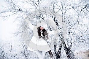 Young beautiful happy girl walking in park. Model wearing stylish winter clothing. Outdoor active fun.