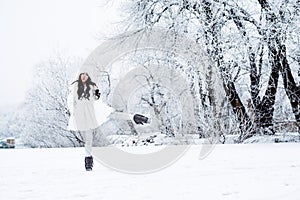 Young beautiful happy girl walking in park. Model wearing stylish winter clothing. Outdoor active fun.