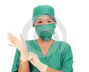 Young beautiful and happy medicine doctor or chief hospital nurse in green scrubs and surgey hat and mask wearing protective latex