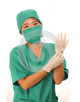 Young beautiful and happy medicine doctor or chief hospital nurse in green scrubs and surgey hat and mask wearing protective latex