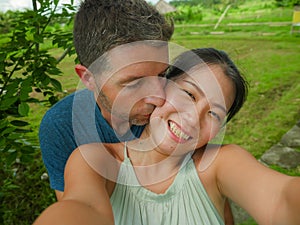 Young beautiful and happy mixed ethnicity couple beautiful Asian Chinese woman and white man in love taking selfie picture