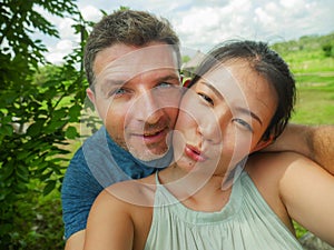 Young beautiful and happy mixed ethnicity couple beautiful Asian Chinese woman and white man in love taking selfie picture