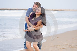 Young beautiful and happy mixed ethnicity couple of Asian woman and Caucasian man relaxed and cheerful walking playful  on beach