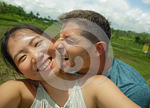 Young beautiful and happy mixed ethnicity couple beautiful Asian Chinese woman and white man in love taking selfie picture