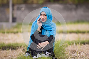 Young beautiful and happy muslim woman wearing islamic hijab head scarf and traditional clothing talking on mobile phone smiling c