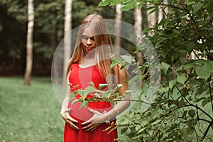 Young beautiful and happy pregnant girl walks in a park by the lake. The benefits of walking during pregnancy, health care.