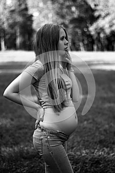 Young beautiful and happy pregnant girl walks in the park. second trimester. Benefits of walking during pregnancy, health care.