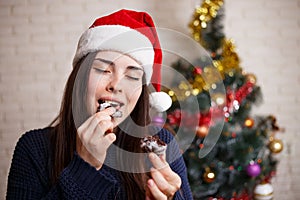 Young beautiful happy surprised woman in Santa cap biting ginger