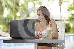 Beautiful happy woman in Summer dress outdoors at nice coffee shop having breakfast networking or working with laptop computer