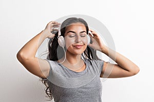 Young beautiful happy woman with headphones in studio, eyes closed.