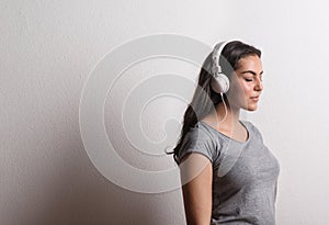 Young beautiful happy woman with headphones in studio, eyes closed. Copy space.
