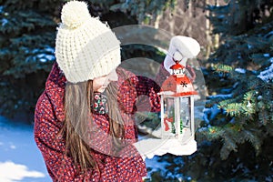 Young beautiful happy woman with red Christmas lantern in the snow