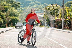 A young beautiful happy woman in sportswear rides a Bicycle. In the background, the road and mountains, a Sunny day. Sports