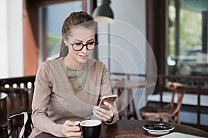 Young beautiful happy woman using smart phone in a cafe, Pretty student girl sitting in a coffee shop