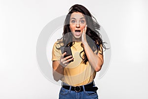 Young beautiful happy woman using smart phone. Excited surprised woman texting on her mobile phone isolated on grey background.