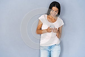 Young beautiful happy woman using smart phone. Isolated on gray background.