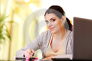 Young beautiful happy woman writing notes