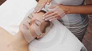 Young, beautiful and healthy woman in massaging salon. Traditional face massage therapy and skin care.