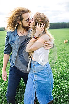 Young beautiful hippie couple walking in green summer field
