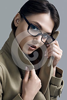 Young beautiful hipster woman in fashionable coat and glasses