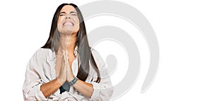 Young beautiful hispanic girl wearing casual clothes begging and praying with hands together with hope expression on face very